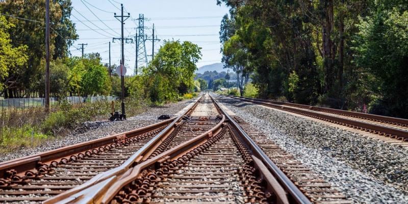 Two train tracks merging into one. The track continues to the horizon.