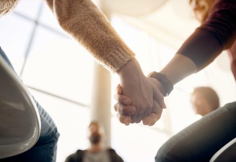 Kuvituskuva, jossa ihmiset pitävät toisiaan kädestä kiinni aurinkoisessa huoneessa.