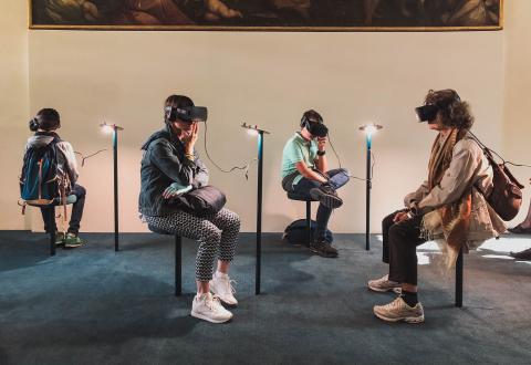 People are sitting with VR-glasses on. 